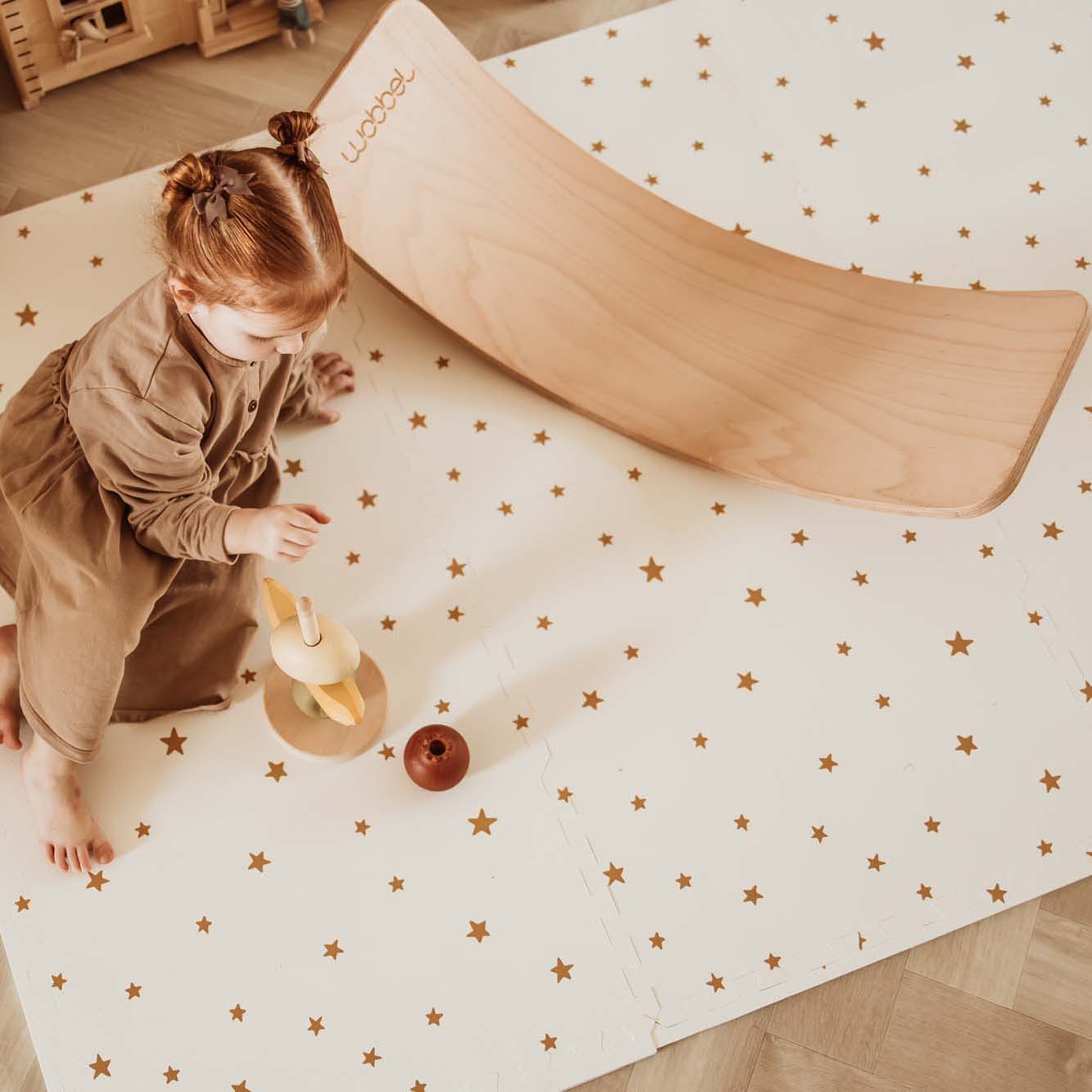 PlayandGo_EEVAA_treehouse_puzzlemat_child_sitting_on_the_mat_with_stars_print_wooden_swing_board_wooden_toys 2 in 1 Spielmatte EEVAA "Tree House" – Bild 16