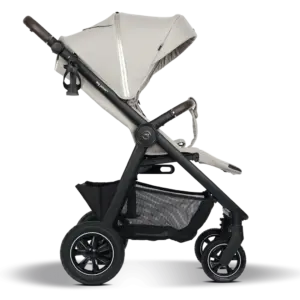 Beige baby stroller with a beige canopy and black frame, large rear wheels, and a lower storage basket viewed from the side.