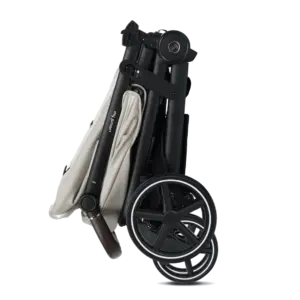 Folded baby stroller with beige fabric and black frame, wheels visible on side.