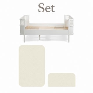 White wooden baby crib with slatted base and curved end rails; two beige quilted mattress pads nearby readied as a Set option.