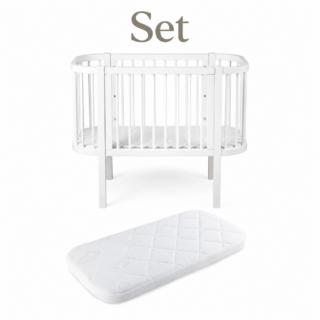 White circular baby crib with vertical slats and a separate white quilted crib mattress set against a white background.
