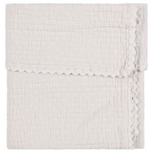 Cream-colored textured towel folded flat with decorative lace trim along the edge surface folds.