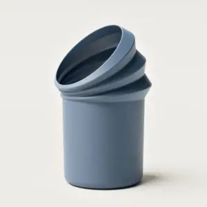 Blue collapsible silicone cup with stacked curled rims, standing upright on a light background.