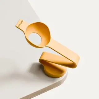 Orange silicone page holder clip resting on a white notebook, designed to hold pages open smoothly.