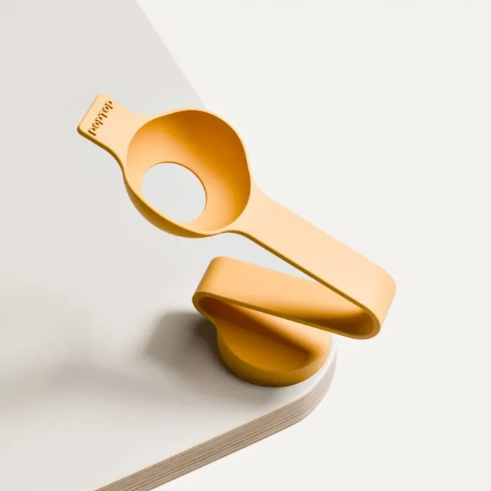 katapult1 Orange silicone page holder clip resting on a white notebook, designed to hold pages open smoothly.