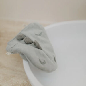 Gray sock draped over the rim of a white bowl on a light countertop.