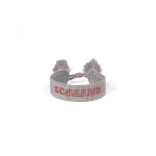 Beaded bracelet with the word SCHULKIND embroidered in red on a pale band and two tassels at the ends.