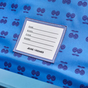 White form with fields for Name, School, Phone, and Address resting on blue fabric with a repeating cherry pattern.