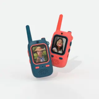Two colorful kiddie walkie-talkies with screens showing smiling faces, blue and coral hues, angled as if in use.