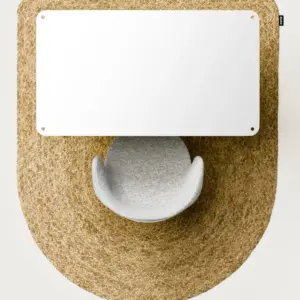 Top-down view of a white rectangular desk panel over a circular woven rug with a gray curved chair beneath.