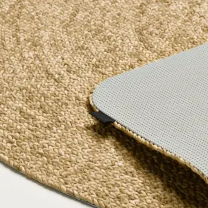 Close-up of a beige woven jute rug with a gray perforated mat partially lifted on top.